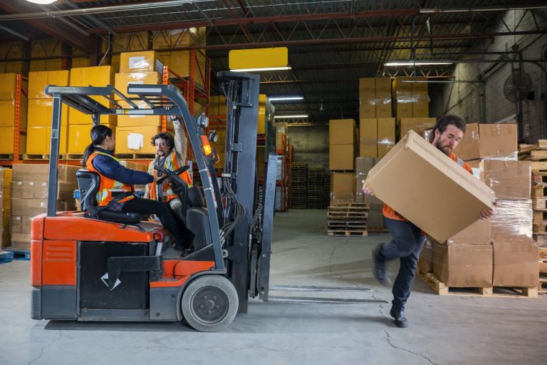 An industrial warehouse workplace safety topic. A male employee injured by tripping over forklift forks. Forks must be placed on the ground to avoid being trip hazards.